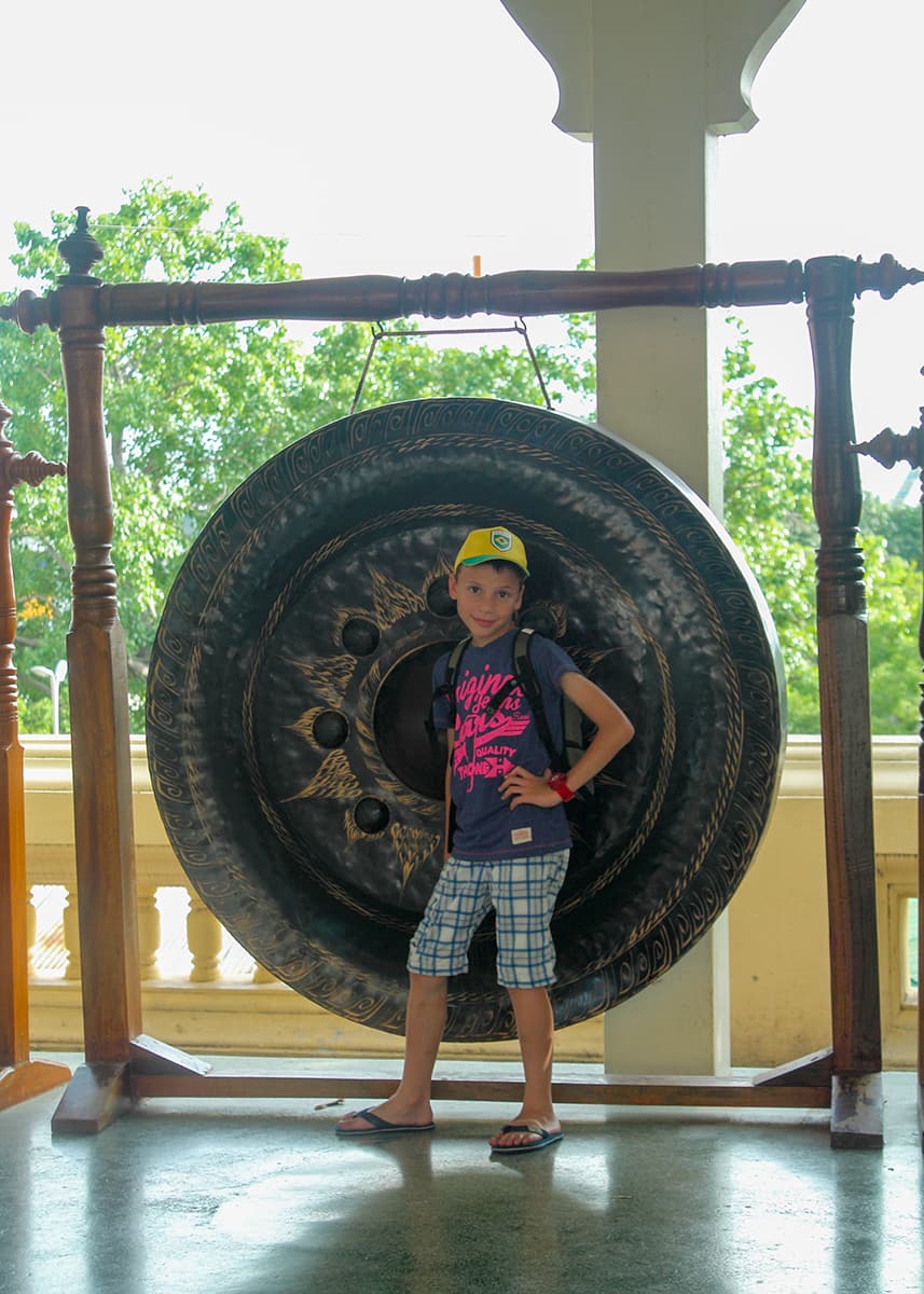 A boy poses in front of a gong at Wat Phra Pathom Chedi in Nakhon Pathom