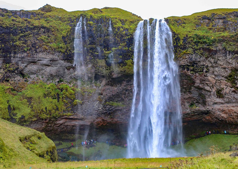 A waterfall cascading down a rocky cliff surrounded by lush green moss at Seljalandsfoss in Iceland