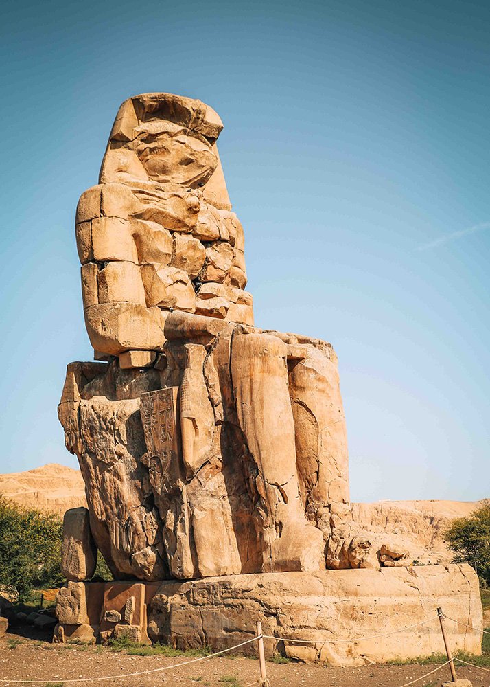 Close-up of one of the Colossi of Memnon, highlighting the detailed carvings and erosion on the stone statue.