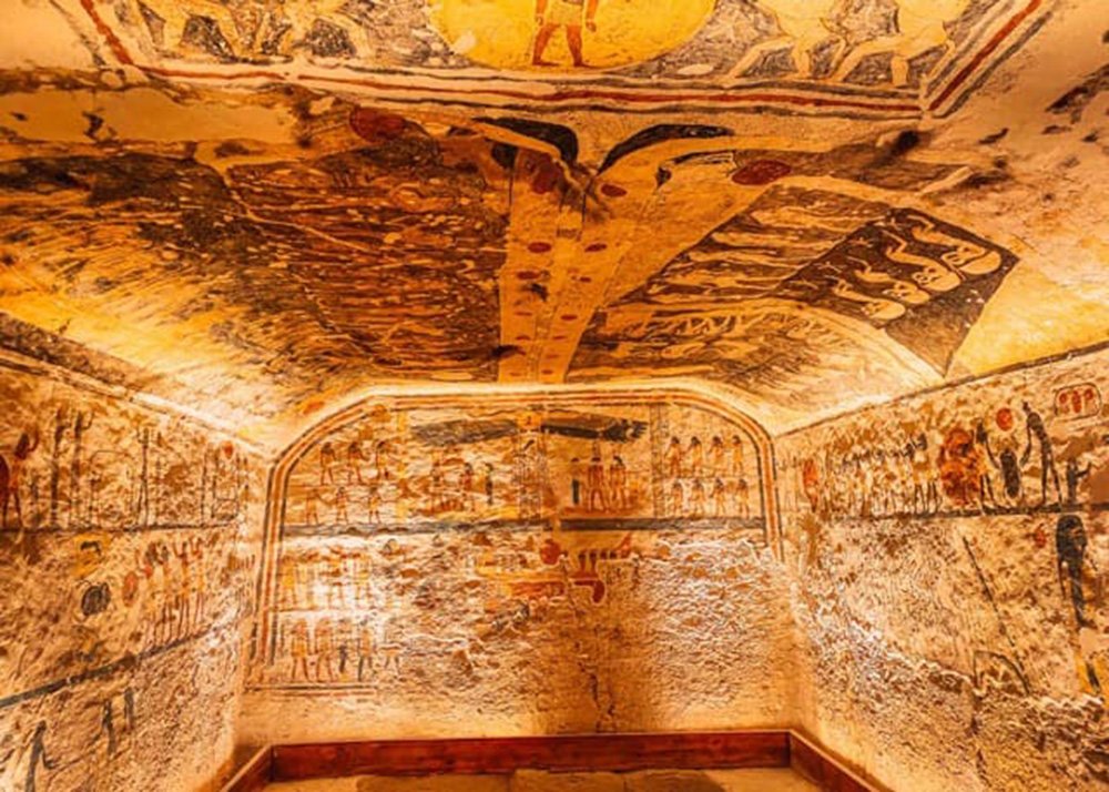 Interior of an ancient Egyptian tomb, with intricate wall paintings and hieroglyphs.