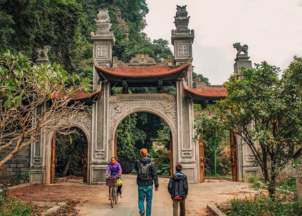 A man and his son or walking towards an old Chinese gate in Vietnamese town Ninh Binh in the Old Quarter