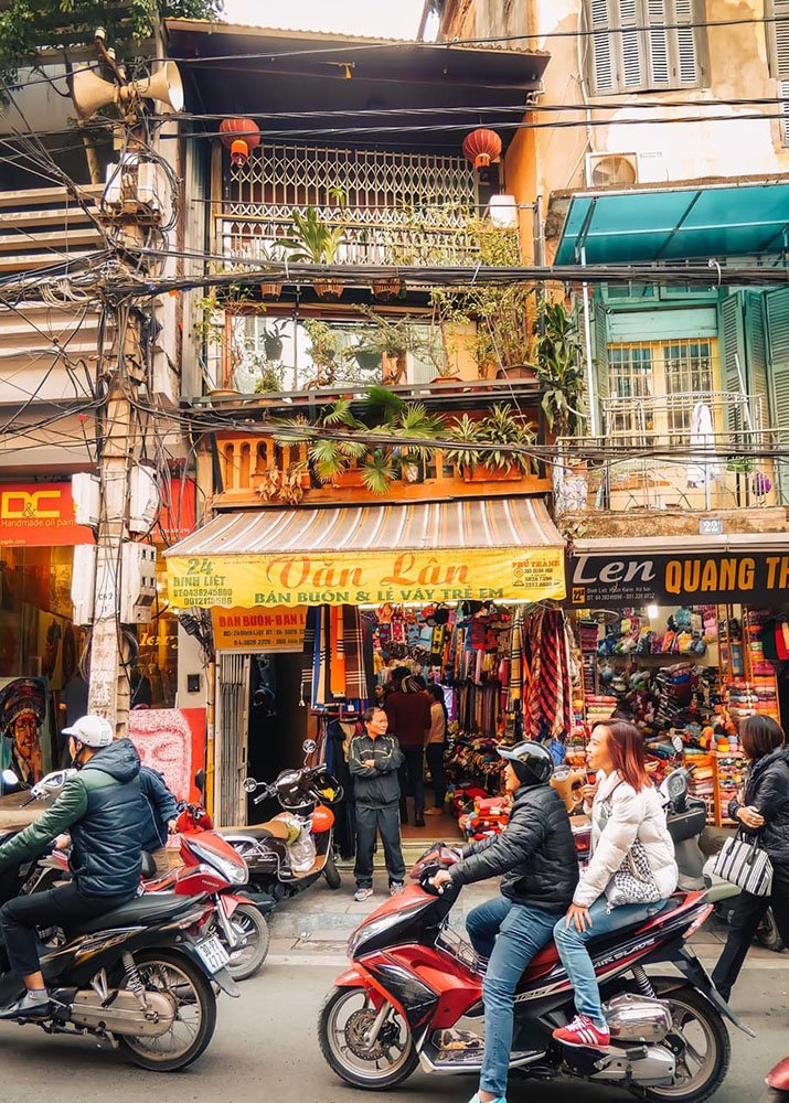 The busy Old Quarter of Hanoi - Vietnam: A lively street in Hanoi's Old Quarter filled with shops and motorbikes.