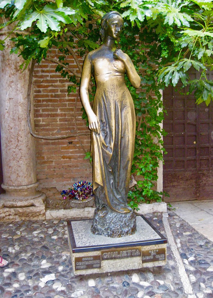 Juliet's Statue in Verona: The bronze statue of Juliet in Verona, set in a leafy courtyard, symbolizing the city's connection to Shakespeare's timeless love story, with tourists often seen touching the statue for good luck.