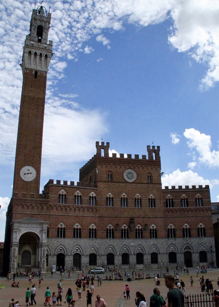 Piazza del Campo in Siena: A view of the Piazza del Campo in Siena, showcasing the tall Torre del Mangia and the Palazzo Pubblico, with families and tourists enjoying the open square under a partly cloudy sky.