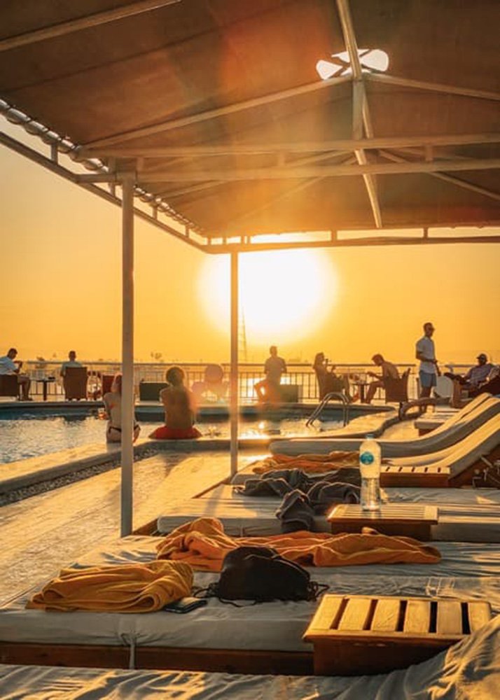 Cruise ship pool deck at sunset with lounge chairs and people relaxing, the sun setting in the background over the Nile.