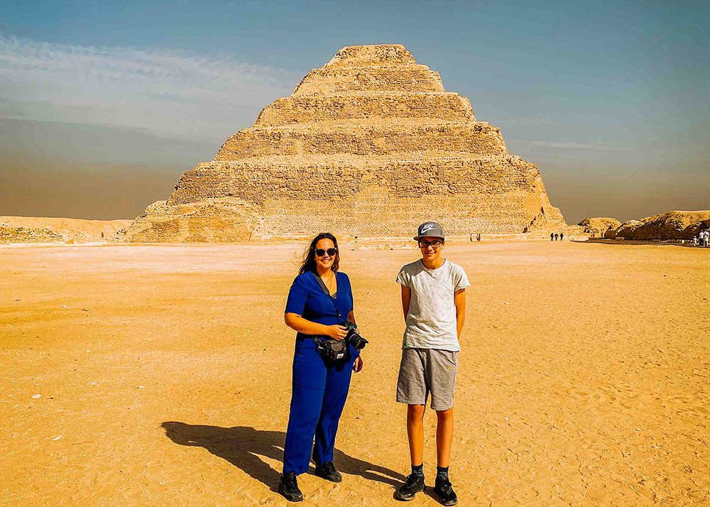 A woman and a boy standing in front of the Step Pyramid of Djoser at Saqqara.
