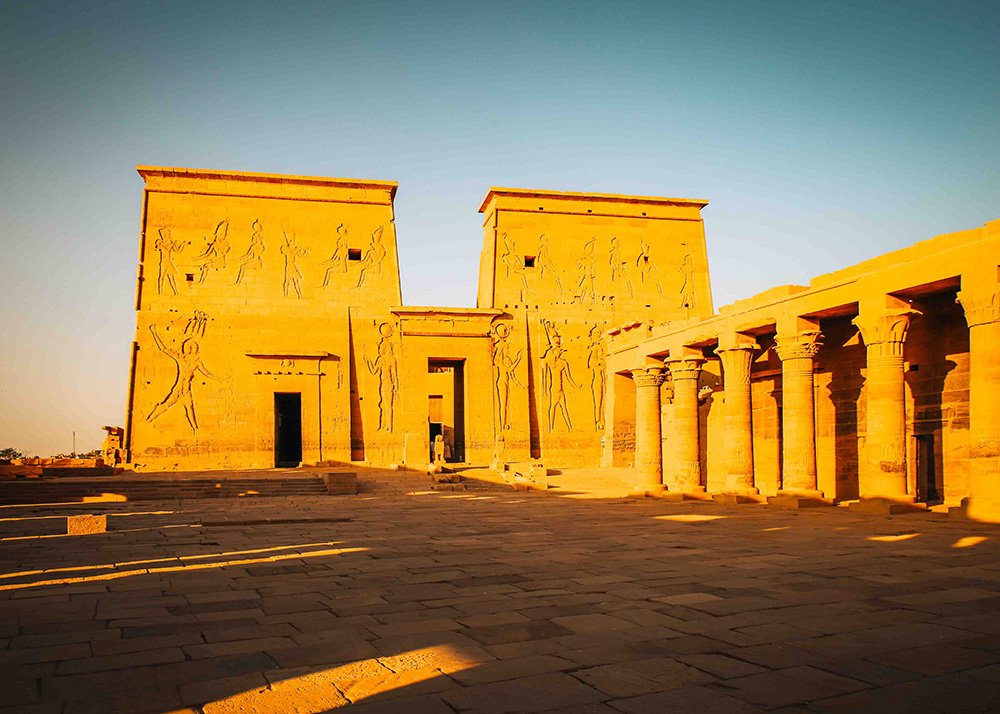 The main courtyard of the Philae Temple with its massive stone walls and pillars adorned with carvings.