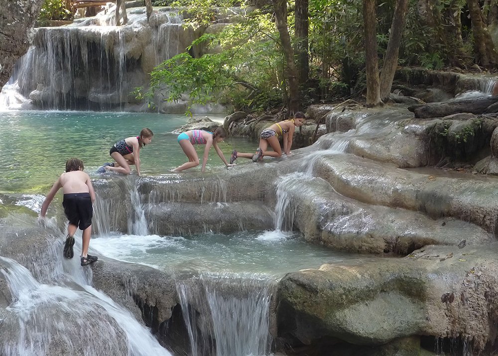 Children playing in the cascading waterfalls at Erawan National Park, Thailand.