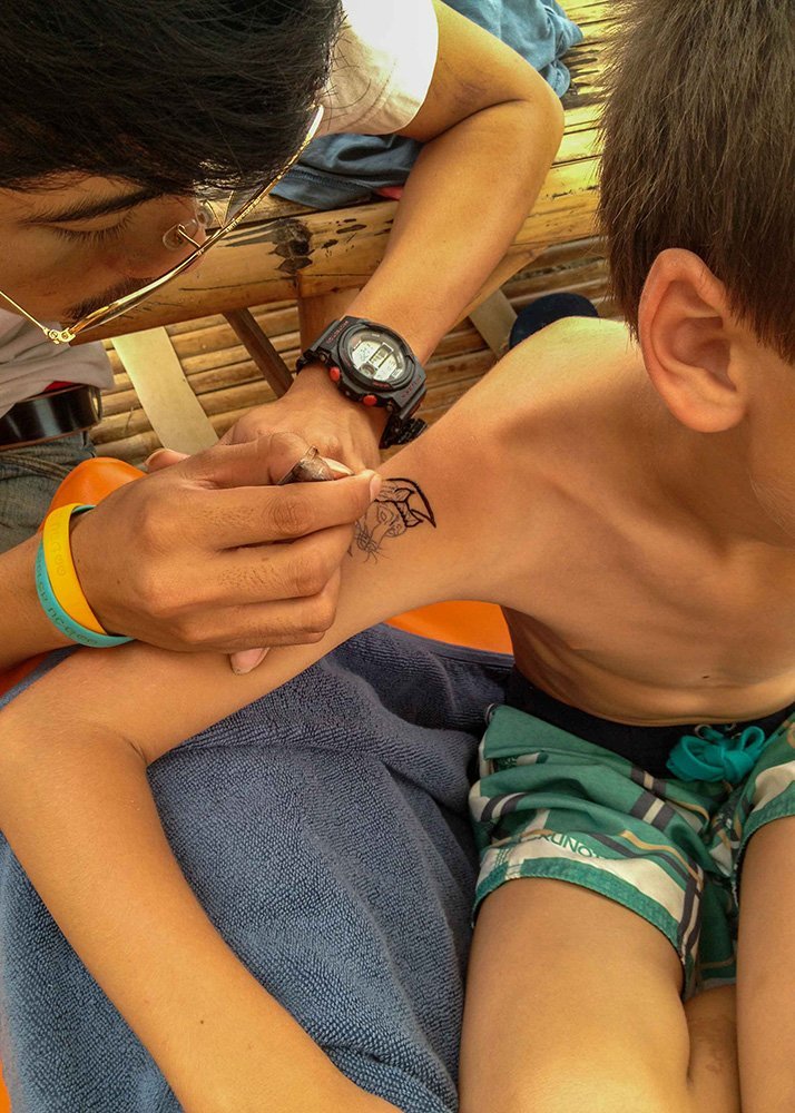 Boy getting a henna tattoo on his arm at Koh Samet, Thailand.