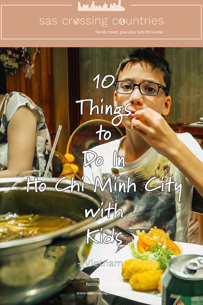 Cover image for a family travel blog post titled "10 things to do in Ho Chi Minh City with kids" showcasing a boy eating a spring roll with a large hot pot in front of him and a plate with spring rolls and a 7up. The blog URL "www.sascrossingcountries.com" is visible at the bottom.