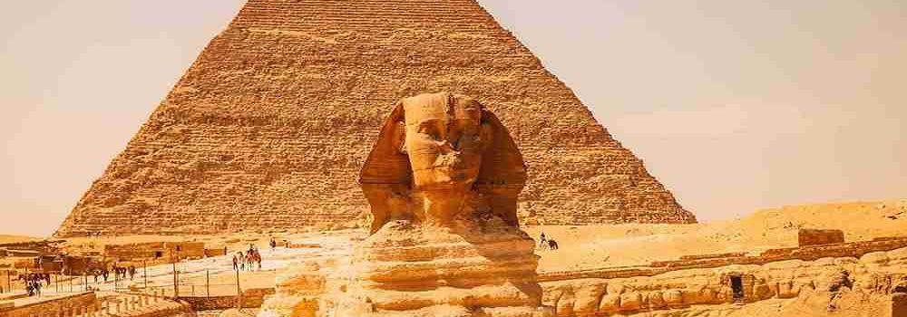 The Great Sphinx of Giza with the Pyramid of Khafre in the background, under a clear sky.