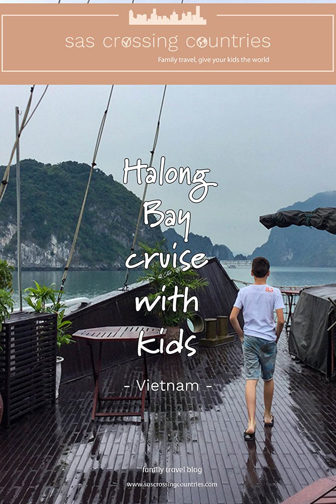 Cover image for a family travel blog post titled "Halong Bay cruise with kids" showcasing a boy walking on the deck of a cruise ship with a dark wooden floor. He has his hands in his pockets and is admiring the view of Halong Bay. The blog URL "www.sascrossingcountries.com" is visible at the bottom.