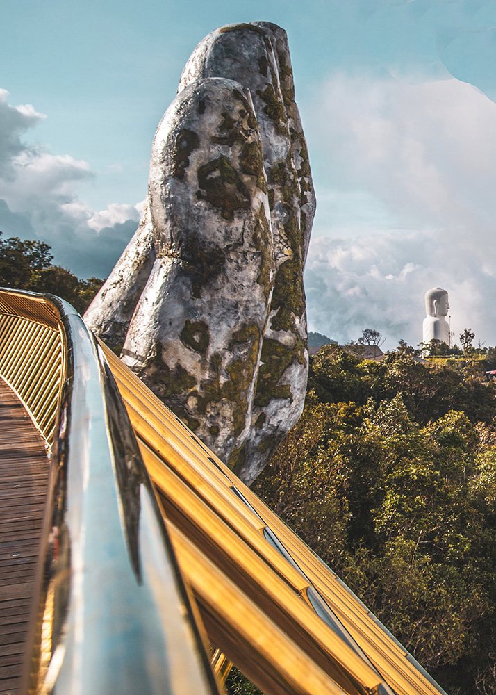 The Golden Bridge near Da Nang, with its striking design of giant stone hands supporting a gleaming walkway, surrounded by lush forest and misty mountains. The bridge offers a surreal and awe-inspiring experience for families, with panoramic views and unique photo opportunities.