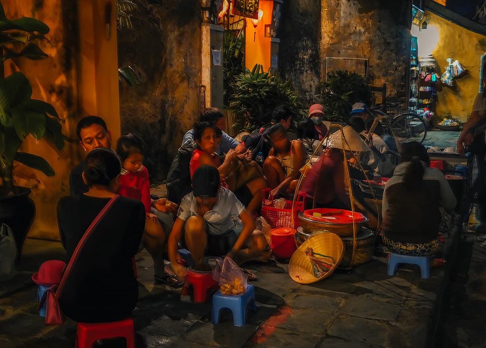 Locals eating outside in Hoi An - Vietnam: Residents enjoying a meal outdoors, capturing the communal dining culture of Hoi An.
