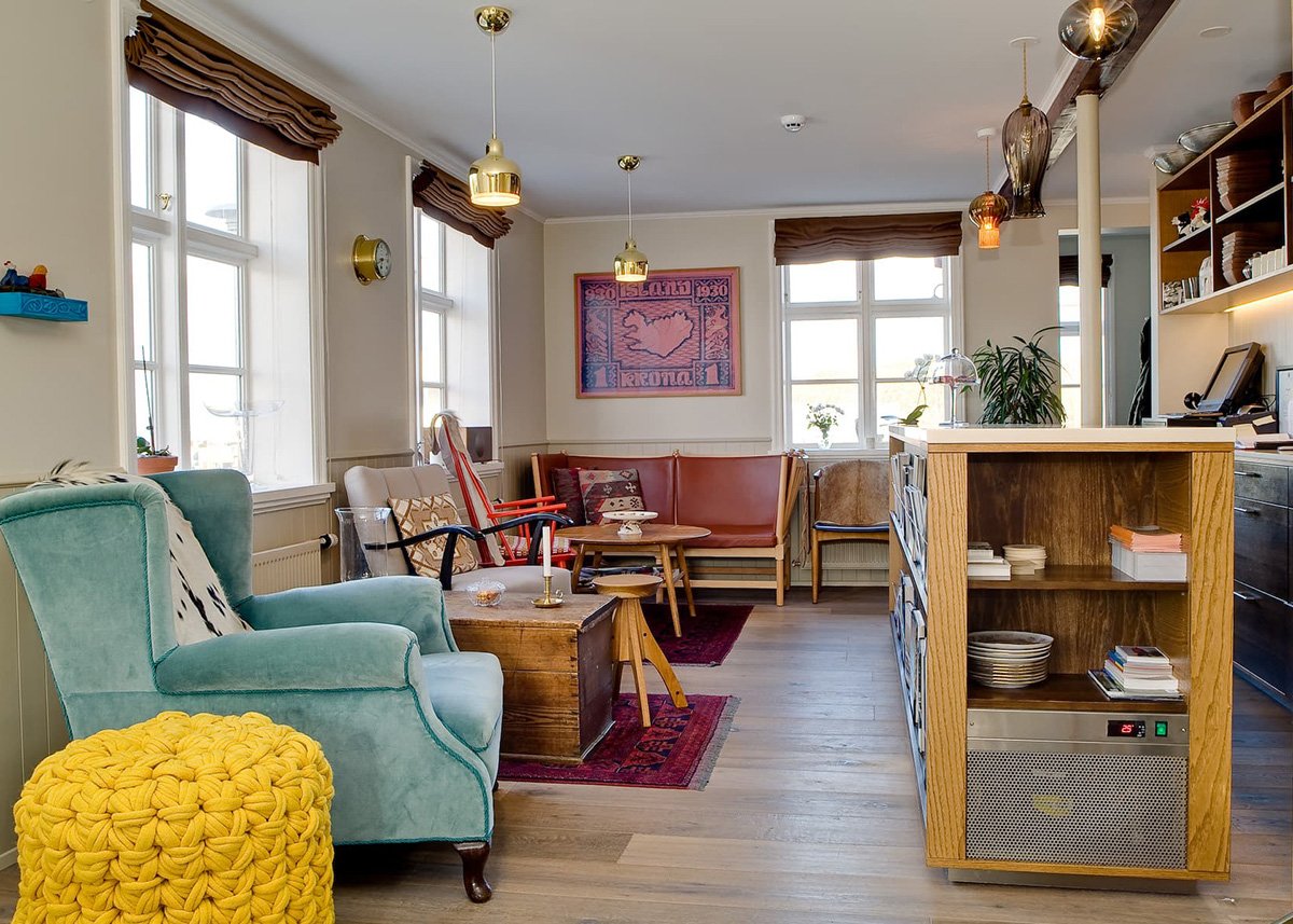 The cosy interior of Hotel Egilsen in Iceland. With different color chairs a map of Iceland on the wall and the reception desk