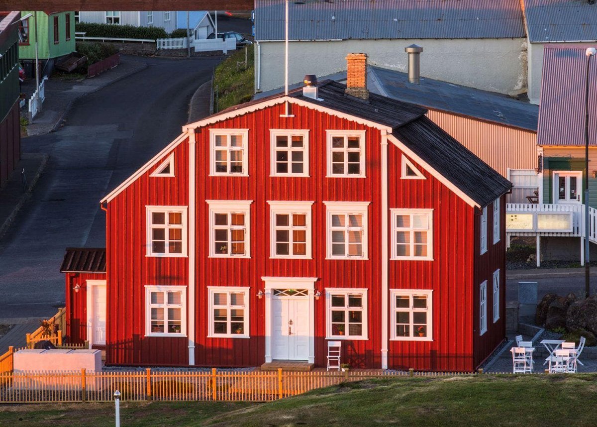 The beautiful Hotel Egilsen from the outside. With a black roof and bright red wooden exterior and window frames painted in white.