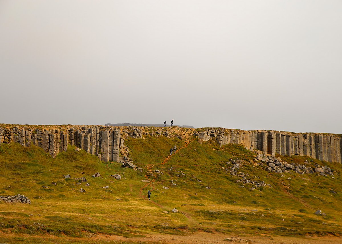 A man and his son walk on top of the Gerduberg Cliffs. The cliffs are massive making the people look like tiny ants