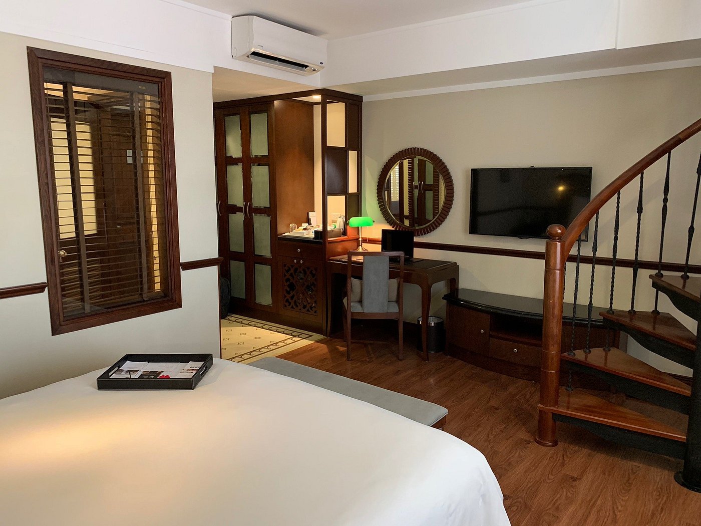 Elegant hotel room at La Siesta Classic Ma May with a spiral staircase, desk space, and warm wooden decor. Great option to consider for accommodations while planning a family trip to Hanoi.