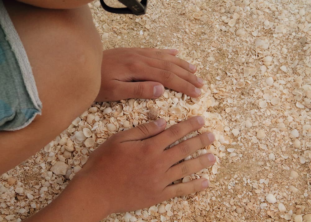 a kid is a making a little pile of tiny shells that fill the entire Shell Beach in Australia. Western Australia with kids.