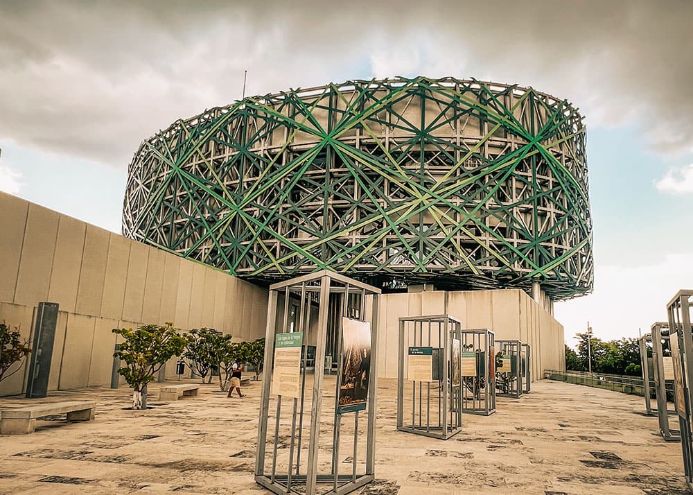 Modern green-and-silver Gran Museo del Mundo Maya exterior with open-air exhibits in Mérida.